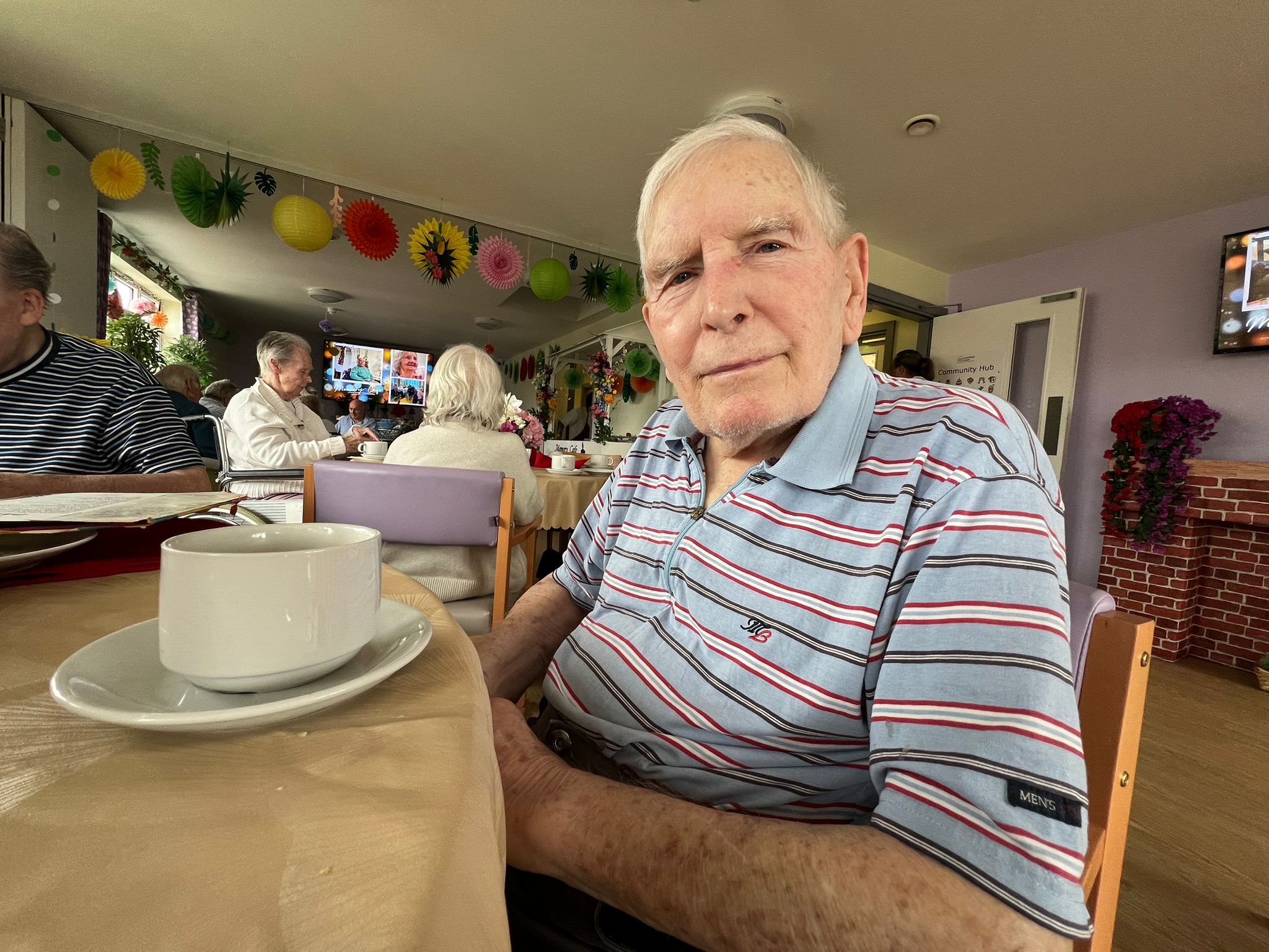 A large group of people gathered around a beach bonfire at dusk.