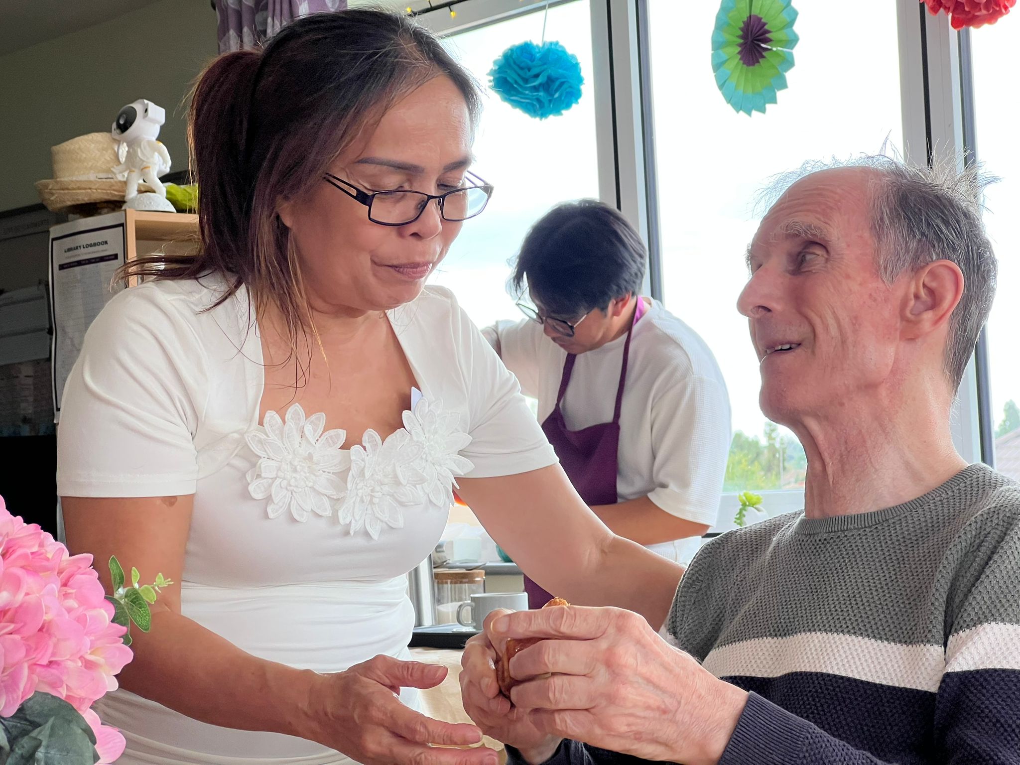 A large group of people gathered around a beach bonfire at dusk.